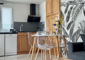 Una cocina moderna con armarios de madera, horno empotrado y comedor con sillas transparentes y una mesa.