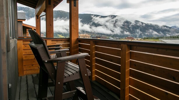 A wooden deck with a chair, overlooking a mountainous landscape with clouds. - Luxury Townhome in the Heart of Big Sky (Big Sky)