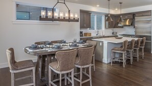 A modern kitchen with a central island, bar stools, and stainless steel appliances. - Luxury Townhome in the Heart of Big Sky (Big Sky)