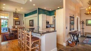 A spacious kitchen with a central island, wooden bar stools, and a dining area with a table and chairs.