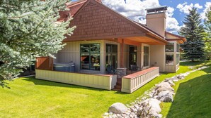 A modern house with a covered porch, stone fireplace, and a well-maintained lawn.