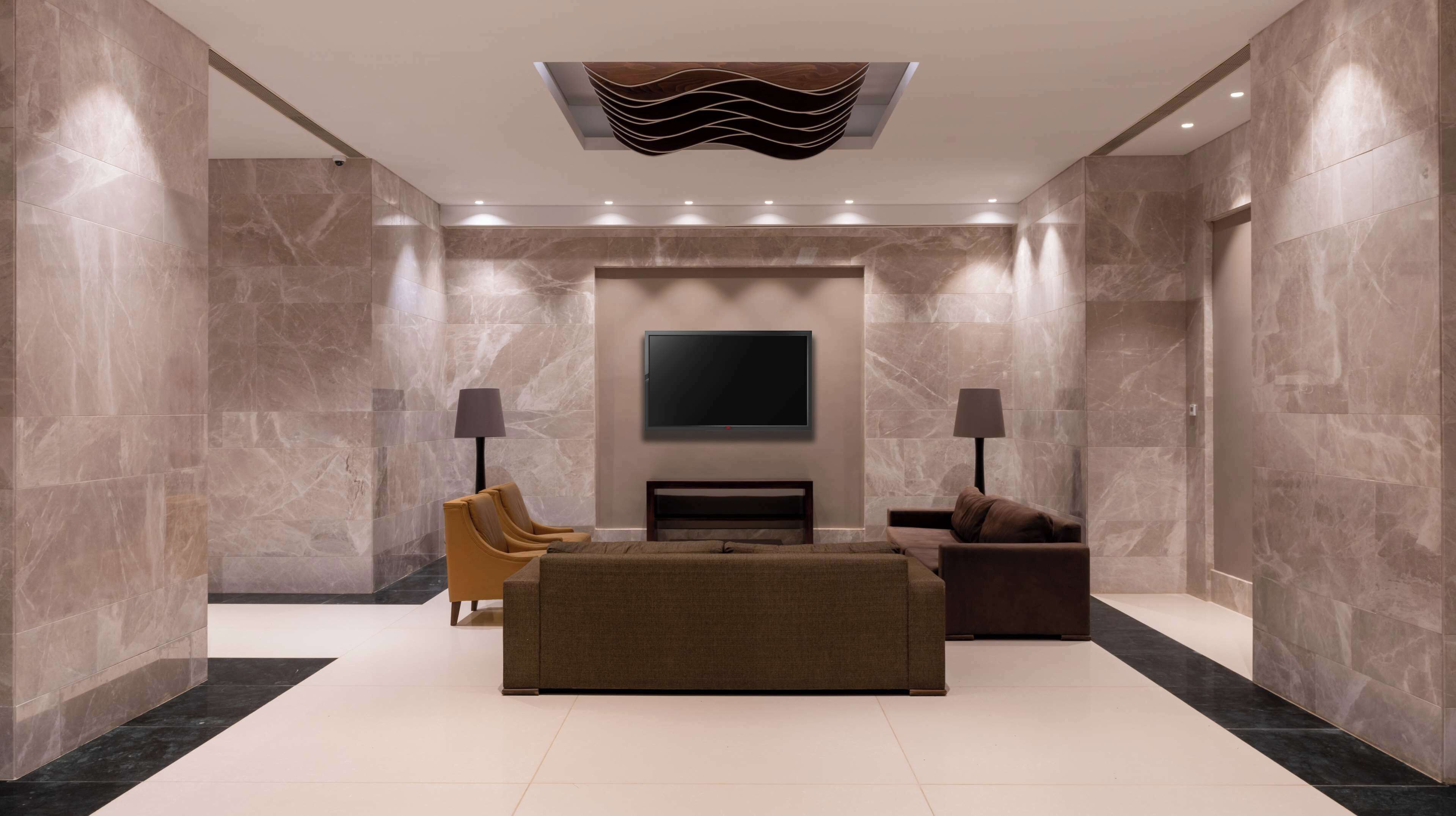 A modern living room with a flat-screen TV, two floor lamps, a sofa, and a coffee table.