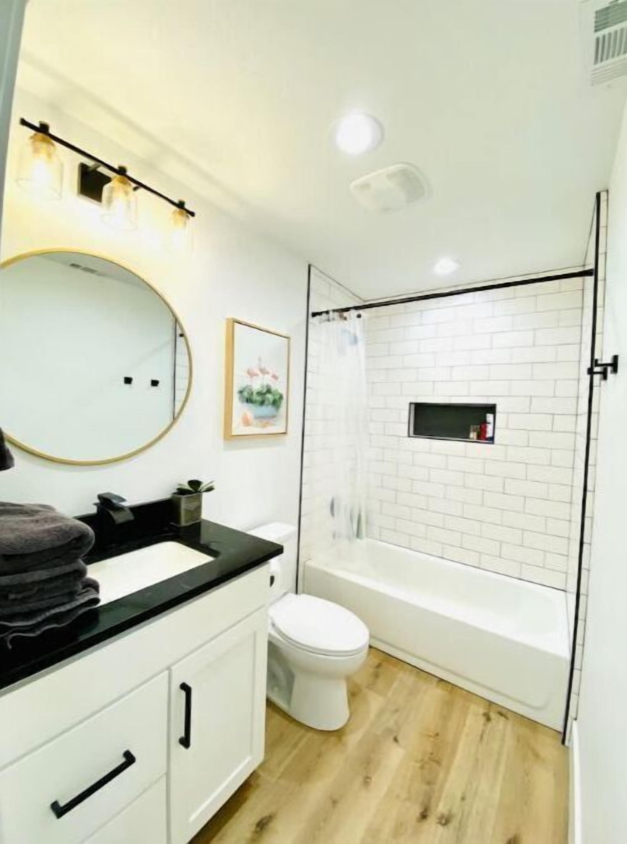A modern bathroom with a white vanity, a toilet, a bathtub, and a shower.