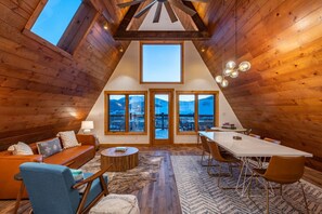A cozy room with wooden walls, a large skylight, a sofa, a dining table, and chairs. - Mid-Century Mountain Home, Fully Remodeled, Style & Comfort in Crested Butte, CO (Crested Butte)