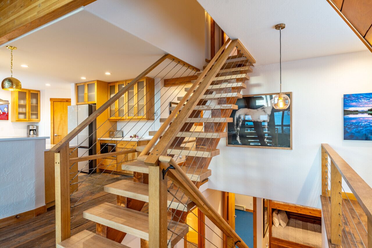 A wooden staircase with a glass railing leading to a second floor.