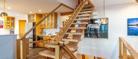 A wooden staircase with a glass railing leading to a second floor.