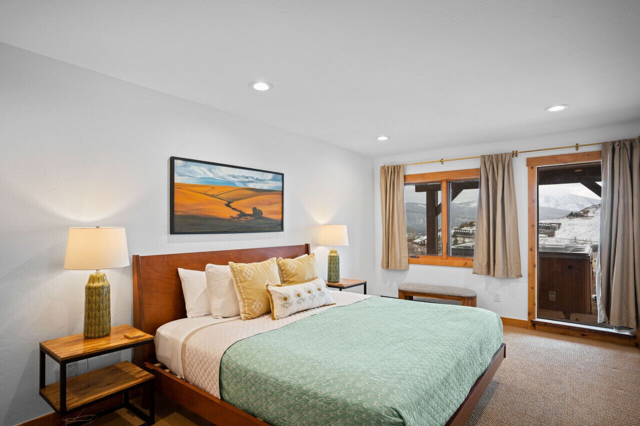 A hotel room with a bed, two bedside tables with lamps, a painting on the wall, and a window with curtains.