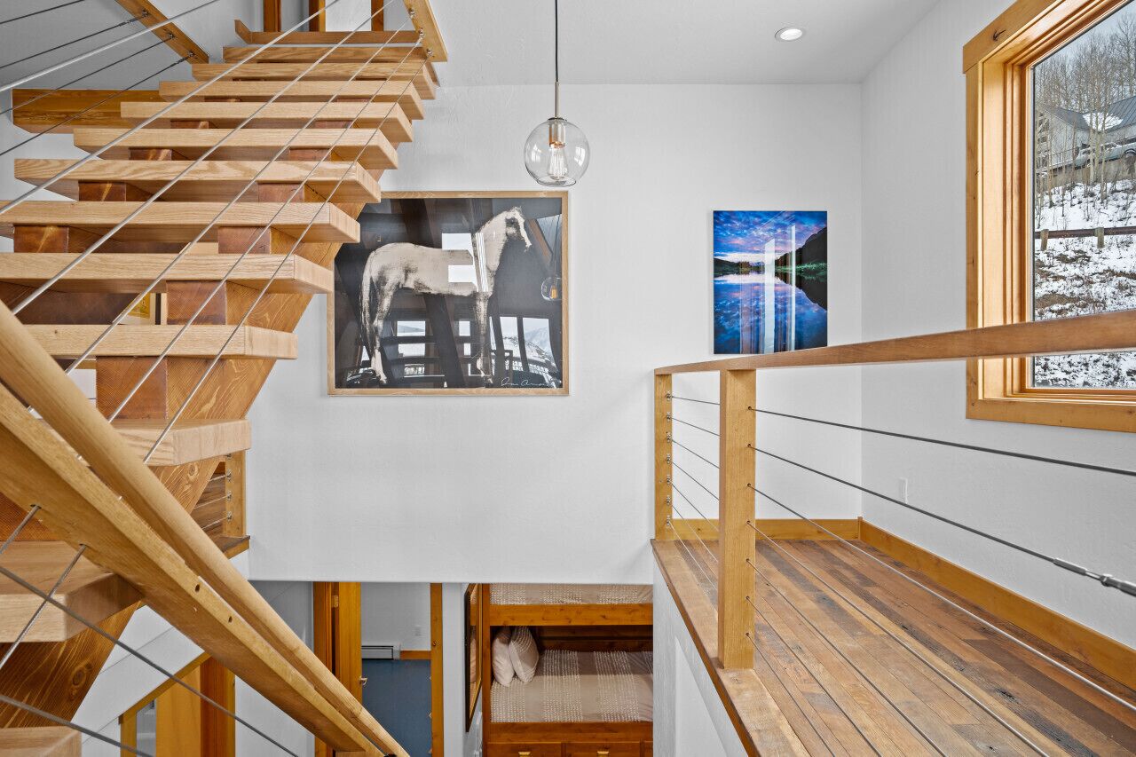 A modern interior with a wooden staircase, a bunk bed, and artwork on the walls.