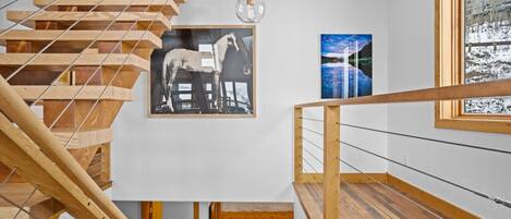 A modern interior with a wooden staircase, a bunk bed, and artwork on the walls.