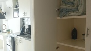 Una cocina moderna con armarios blancos, horno integrado y máquina de café.