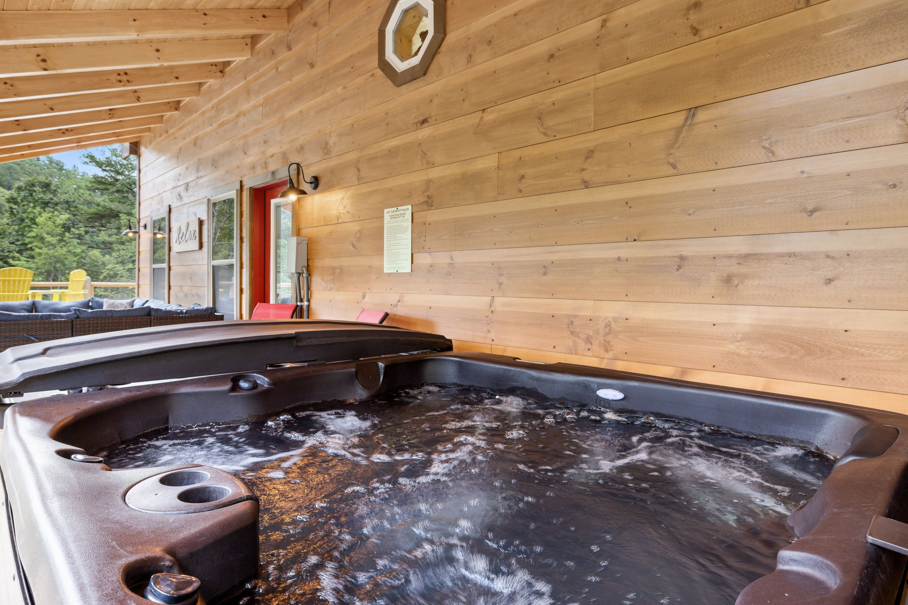 Interno di una baita in legno con vasca idromassaggio, pareti in legno e una porta rossa.