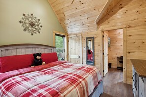A cozy bedroom with a bed, a teddy bear, and a red pillow. - Hidden Cove Chalet 5 Bedroom Cabin by RedAwning (Sevierville)