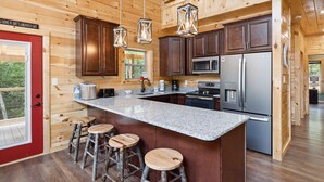 Eine moderne Küche mit Holzwänden, Granitarbeitsplatten, Edelstahlgeräten und einer roten Tür.
