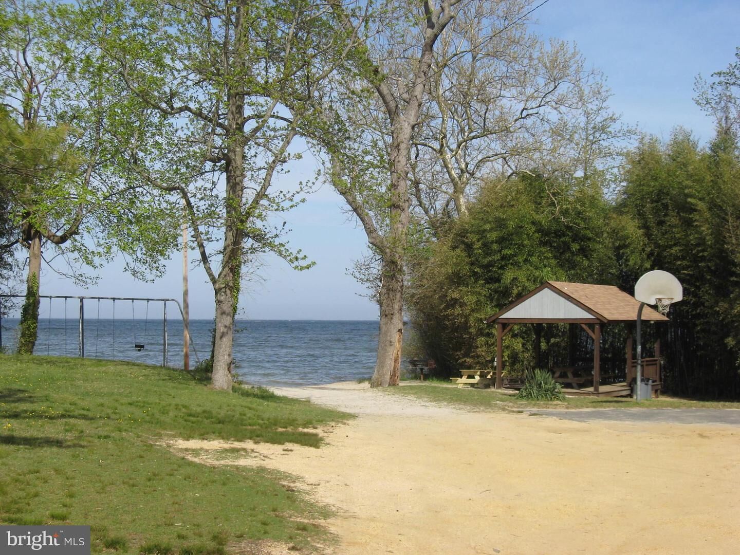 Een strand met een schommel, een basketbalveld en een overdekte kiosk.