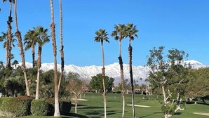 Ein Golfplatz mit Palmen und einer Bergkulisse.