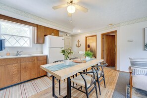 Eine Küche mit Holzausstattung, einem Kühlschrank, einer Spüle und einem Essbereich mit Stühlen und einem Tisch.