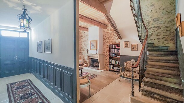 Ein geräumiger Flur mit Kamin, Treppe und Bücherregal.