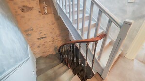 Eine Treppe mit Holzhandlauf und Metallgeländern, die zu einem Zwischenpodest mit einer Steinmauer und einer kleinen Statue führt.