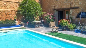 Ein Swimmingpool mit Holzterrasse, einem Liegestuhl und Topfpflanzen.