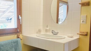 Een badkamer met een wit wastafel, een spiegel en twee rieten manden op een houten plank.