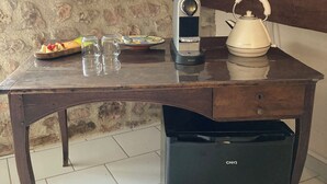 Een keukenhoek met een koffiezetapparaat, waterkoker en een kleine koelkast.