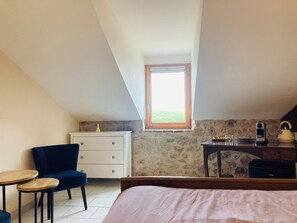 Een slaapkamer met een bed, een bureau, een stoel, een bijzettafeltje en een raam met uitzicht.