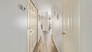 Un couloir avec des portes blanches et un thermostat fixé au mur.