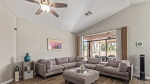 Un salon spacieux avec un grand canapé d’angle, une table basse et un ventilateur de plafond.