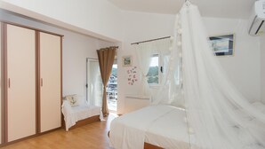 Un dormitorio con cama, armario, ventana con cortinas y vistas al exterior.