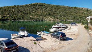 Un puerto deportivo con barcos amarrados, un automóvil y un camino que lleva a un edificio.