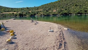 Una playa con agua cristalina, una silla y boyas amarillas.
