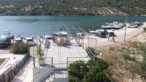 Un puerto deportivo con barcos amarrados, una zona de estacionamiento y vistas al agua y las colinas.
