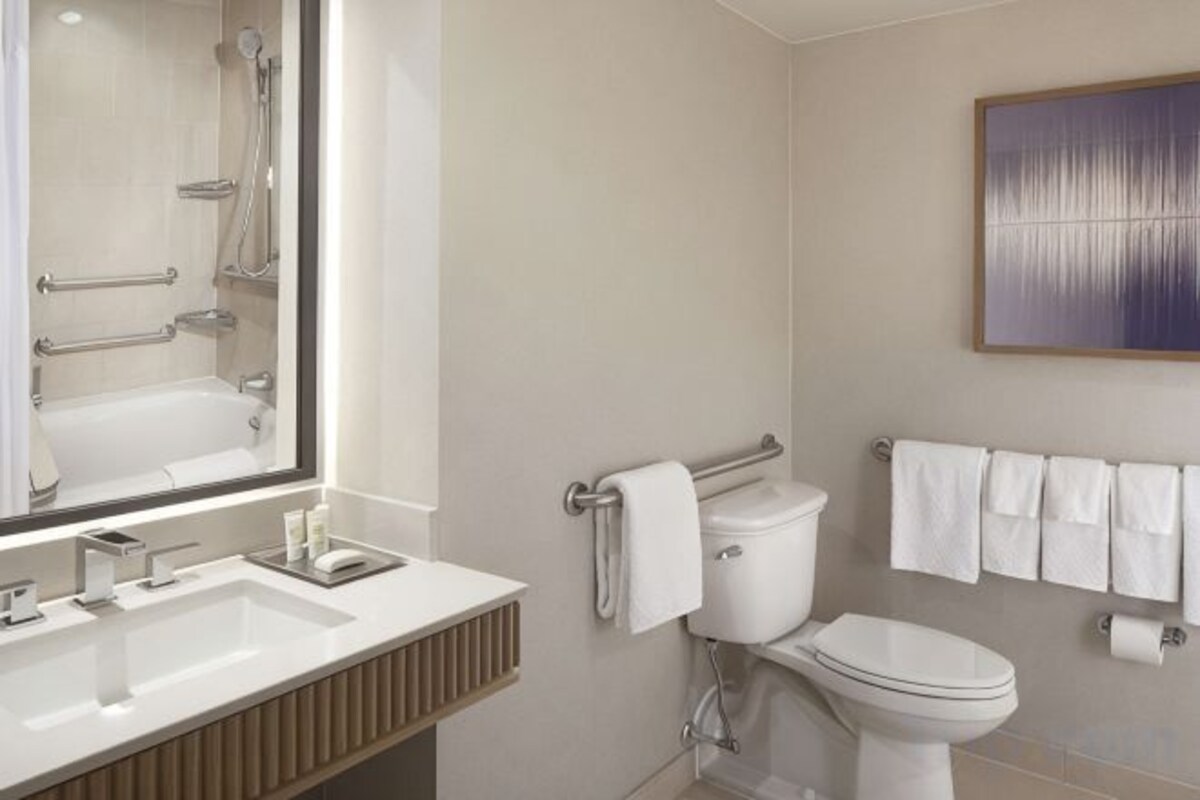Un baño moderno con un espejo grande, un lavabo, un inodoro y un perchero para toallas.