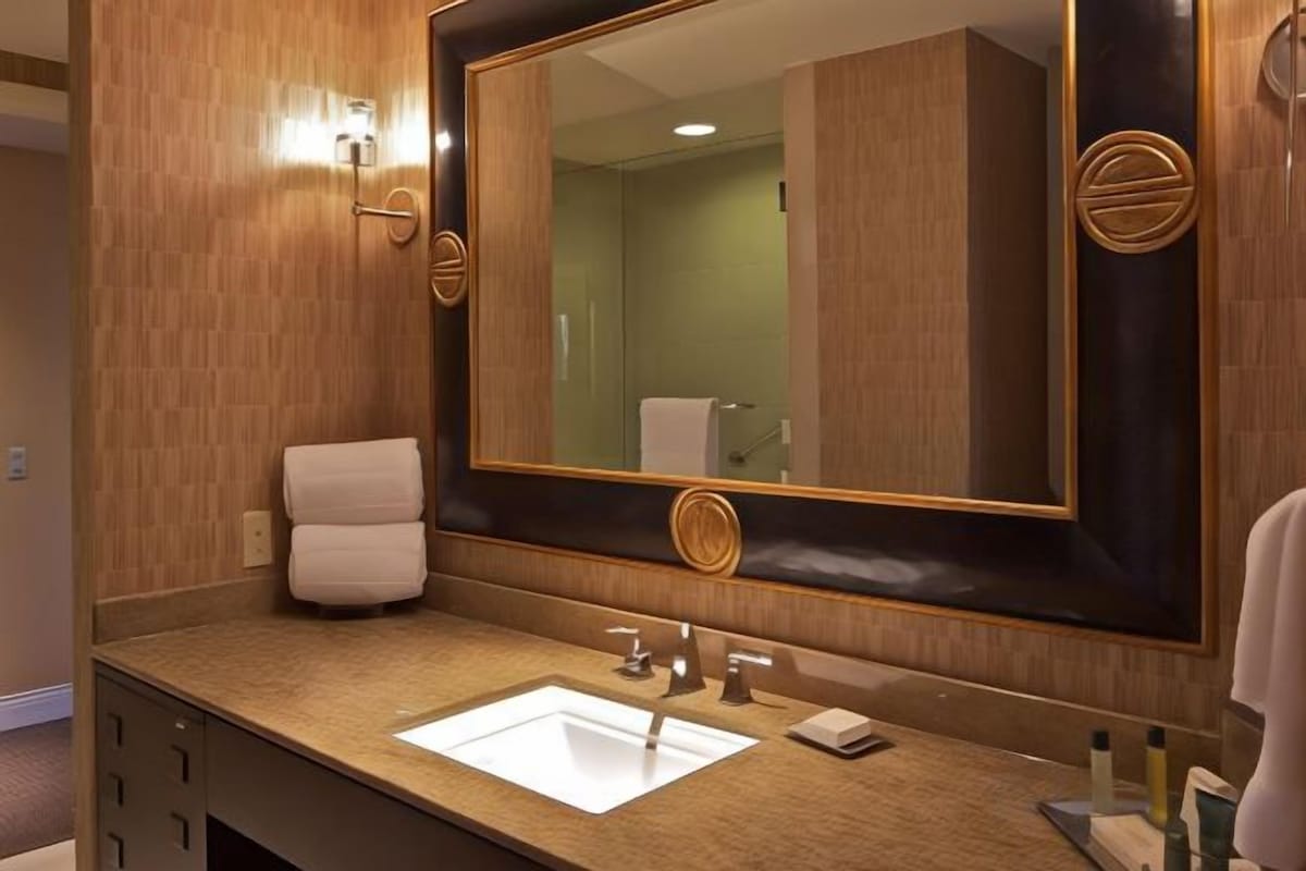 A hotel bathroom with a large mirror, a sink, and a towel rack.