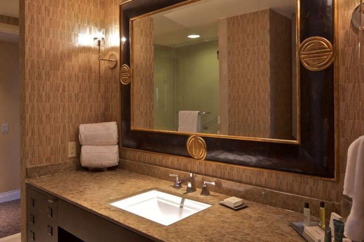 Un baño con un espejo grande, un lavabo y un perchero para toallas.