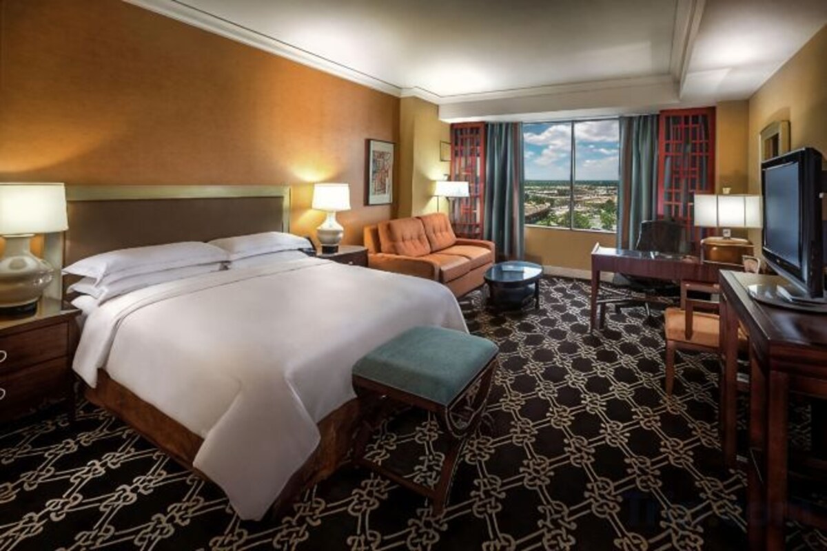 Habitación de hotel con una cama grande, un sofá, un televisor y vistas a la ciudad.