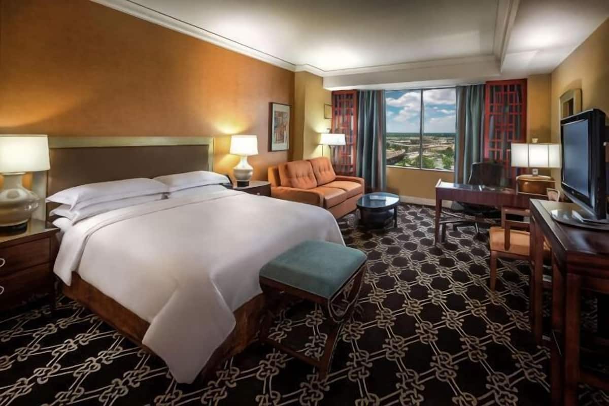Une chambre d’hôtel avec un grand lit, un canapé, une télévision et une vue sur la ville.