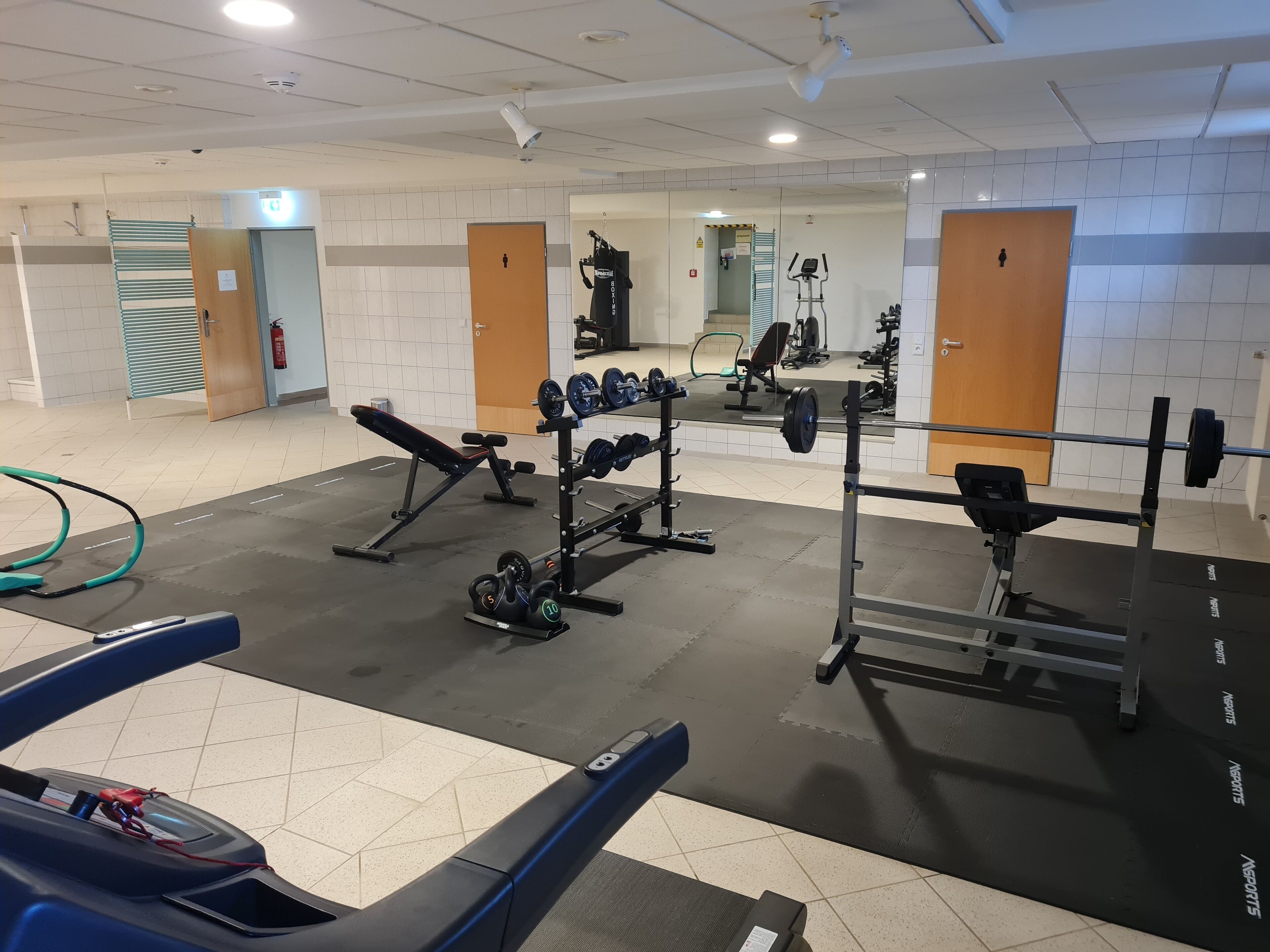 A gym with various exercise equipment, including a bench, dumbbells, and a squat rack.