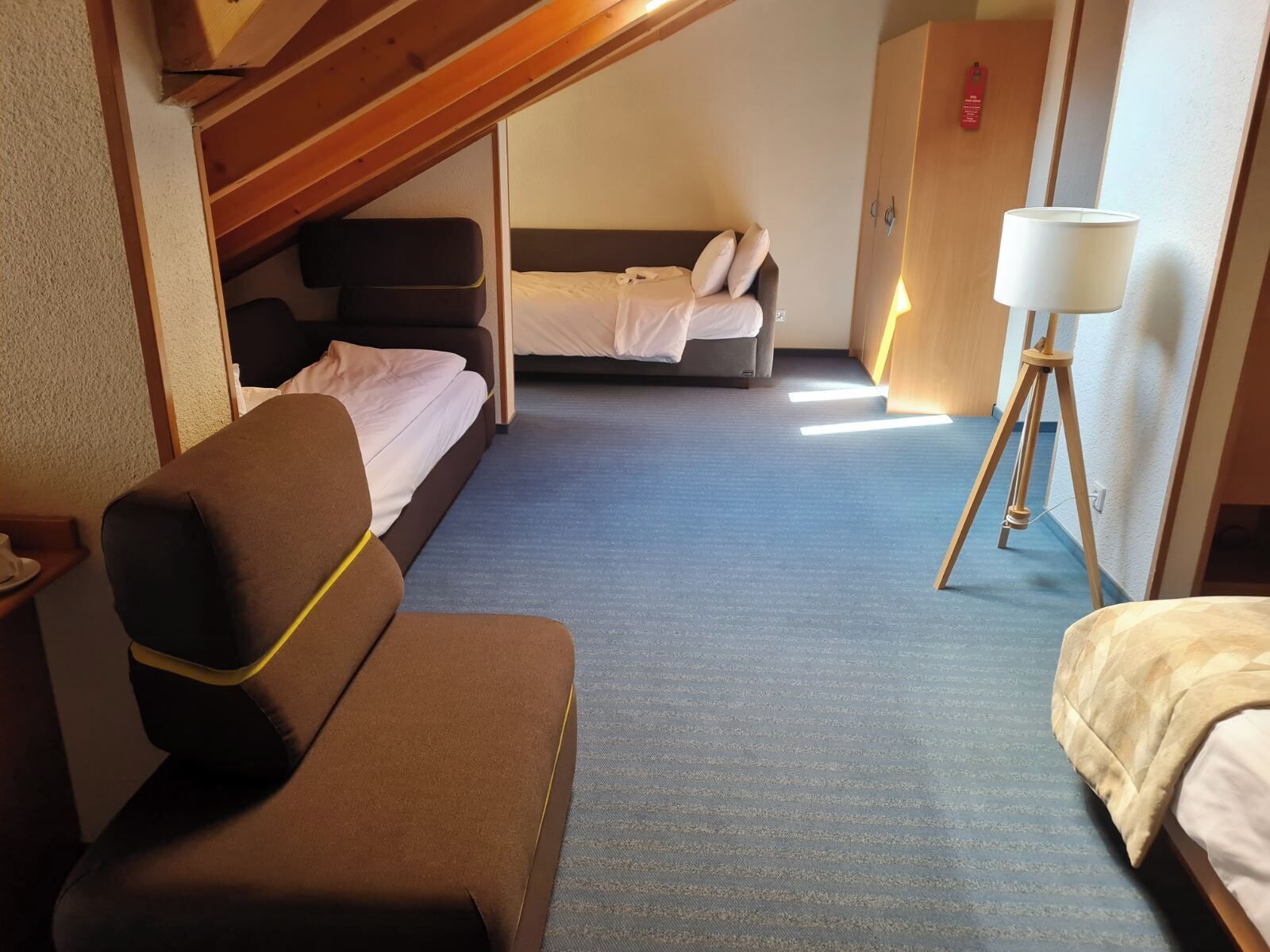 Una habitación de hotel compacta con sofá, cama y un escritorio pequeño.