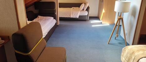 Una habitación de hotel compacta con sofá, cama y un escritorio pequeño.