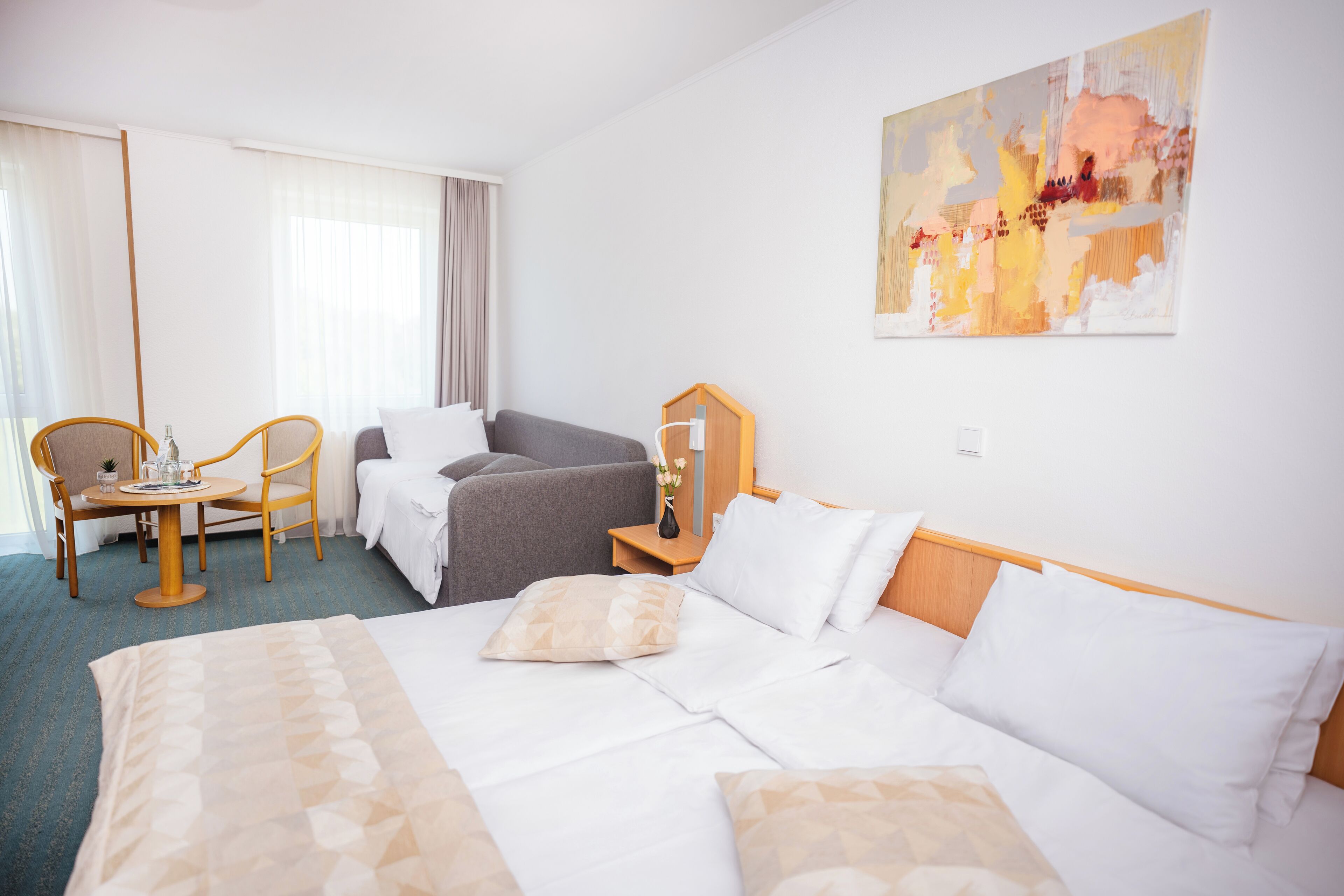 Une chambre d’hôtel avec un grand lit, un canapé, un bureau avec une chaise et un tableau au mur.
