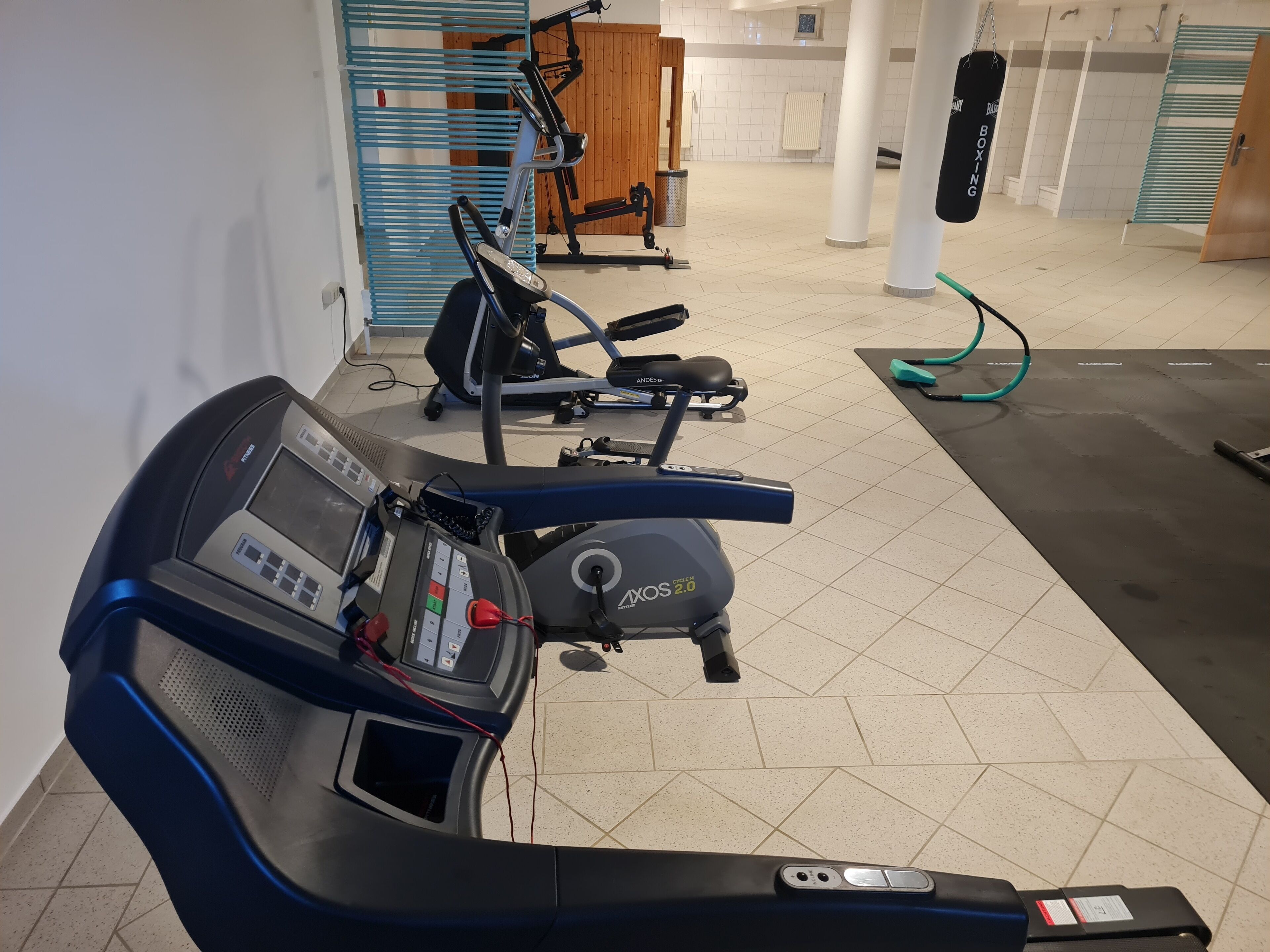 A gym with cardio equipment including a treadmill and an elliptical machine.