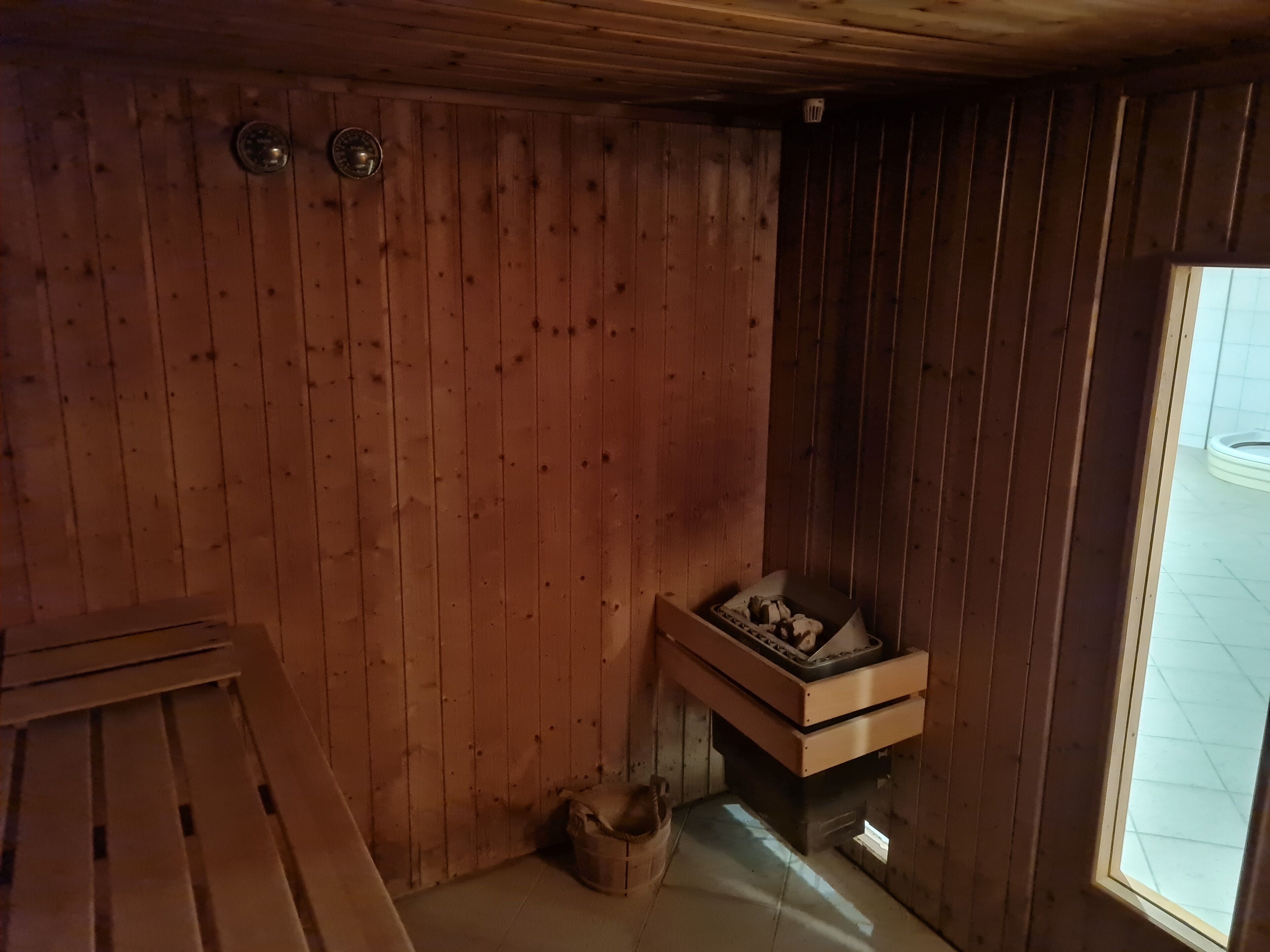Ein Holzhütten-Interieur mit Sauna, einer Holzbank und einem Fenster, das für natürliches Licht sorgt.