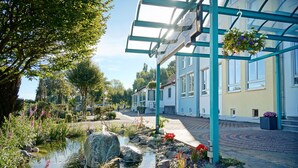 A serene courtyard with a small pond, surrounded by lush greenery and flowering plants. - Hotel Bessunger Forst (Rossdorf)
