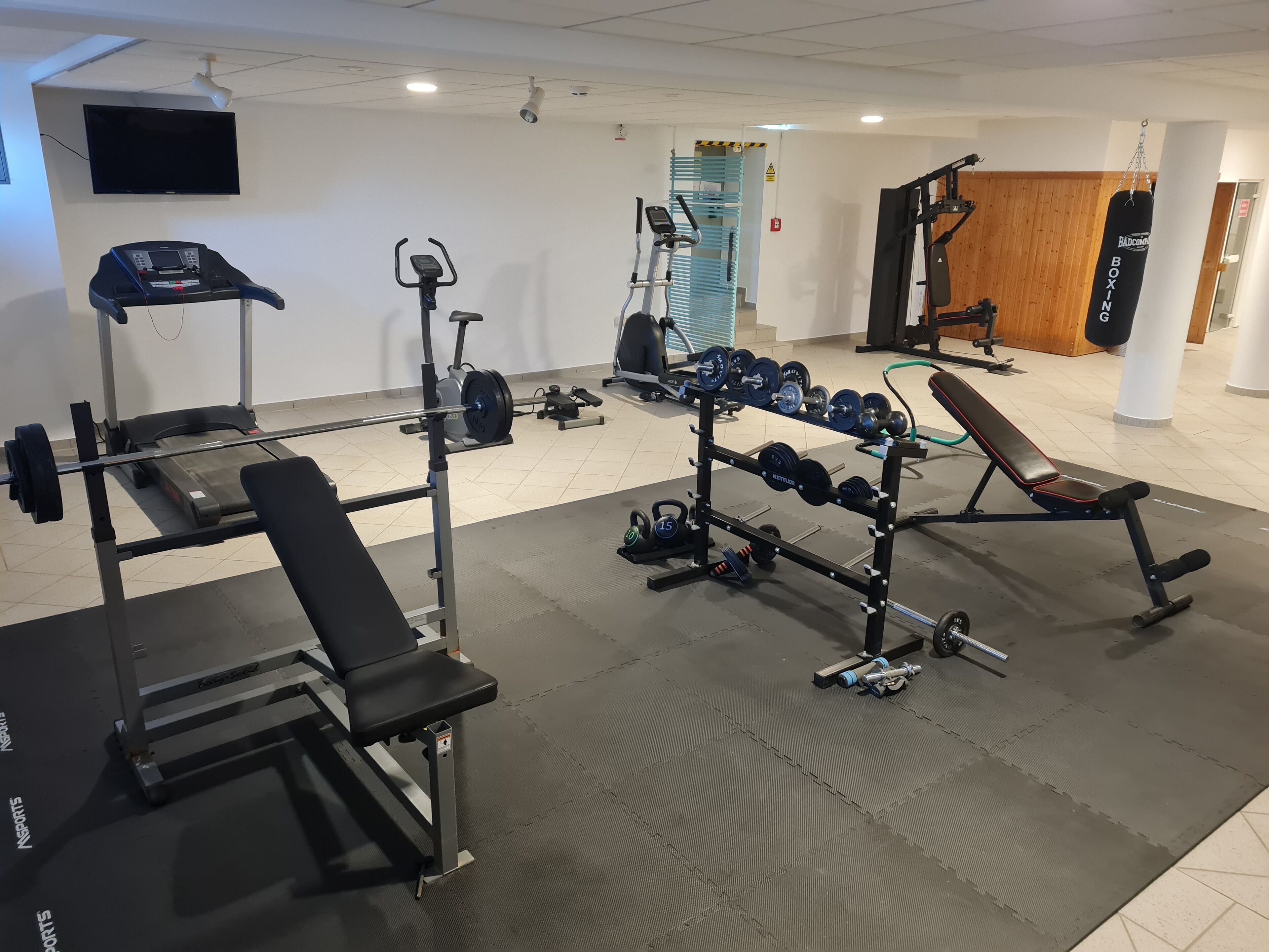 A gym with various exercise equipment, including a treadmill, weight bench, and dumbbells.