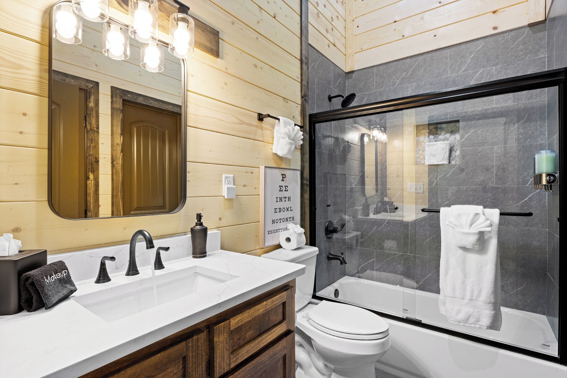A modern bathroom with a wooden vanity, a large mirror, a glass-enclosed shower, and a toilet.