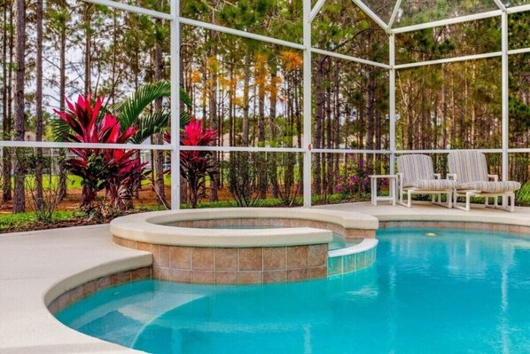 A swimming pool with a covered area, surrounded by trees and plants. - Headline (Davenport)