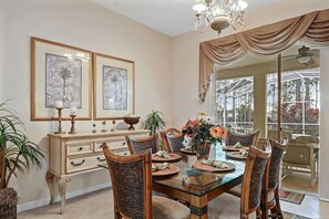A dining room with a glass table, wicker chairs, and a buffet cabinet. - Headline (Davenport)