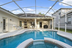 A swimming pool with a glass enclosure, surrounded by lounge chairs and a patio area. - Headline (Davenport)