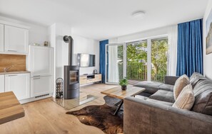 Ein modernes Wohnzimmer mit Kamin, einer Couch, einem Esstisch und Blick ins Freie.